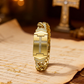 Eine sommerlich anmutende Uhr, verziert mit einem funkelnden Kristallkreuz, einem geometrischen rechteckigen Zifferblatt und einem hochwertigen Metallarmband – eine elegante Wahl für jeden Tag.